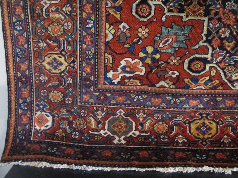 An antique hand-knotted Persian Fereghan wool rug featuring a central terracotta diamond medallion set within a dense navy blue floral field and ornate multi-layered borders. View III
