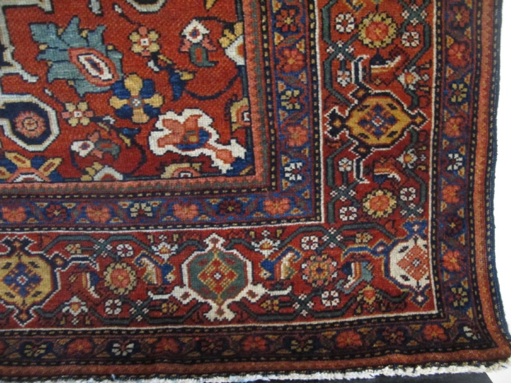 An antique hand-knotted Persian Fereghan wool rug featuring a central terracotta diamond medallion set within a dense navy blue floral field and ornate multi-layered borders. View IV