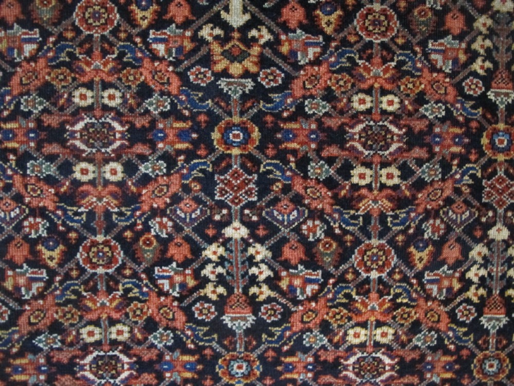 An antique hand-knotted Persian Fereghan wool rug featuring a central terracotta diamond medallion set within a dense navy blue floral field and ornate multi-layered borders. View VI