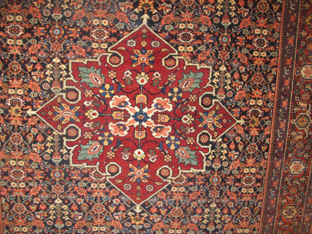 An antique hand-knotted Persian Fereghan wool rug featuring a central terracotta diamond medallion set within a dense navy blue floral field and ornate multi-layered borders. View VII