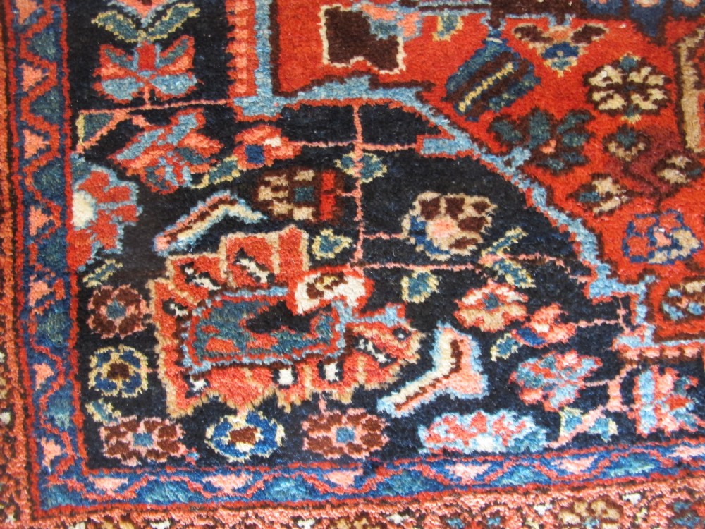 A long hand-knotted antique Persian Hamadan runner rug featuring terracotta red, navy blue, and cream floral medallion motifs throughout the central field. View VI