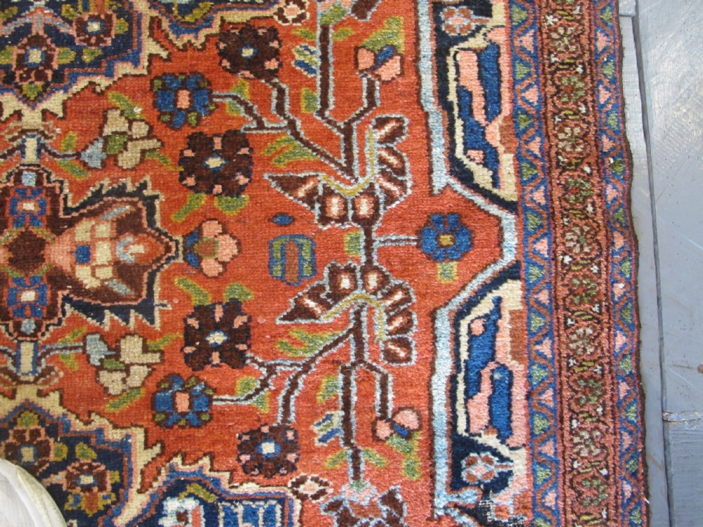 A long hand-knotted antique Persian Hamadan runner rug featuring terracotta red, navy blue, and cream floral medallion motifs throughout the central field. View VIII
