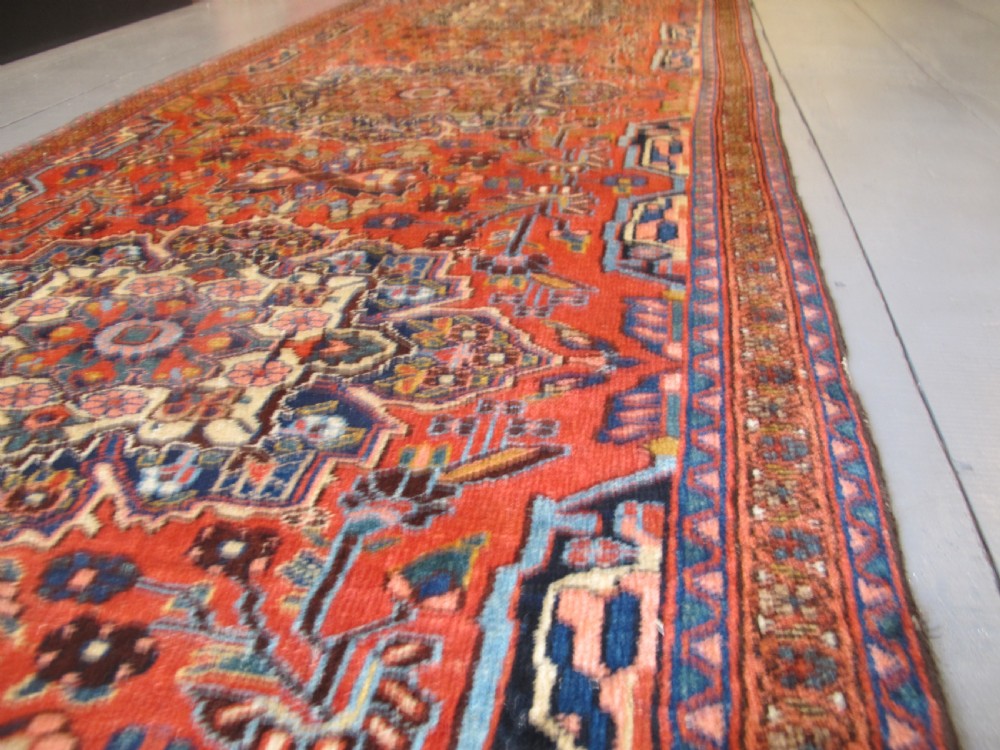 A long hand-knotted antique Persian Hamadan runner rug featuring terracotta red, navy blue, and cream floral medallion motifs throughout the central field. View XI