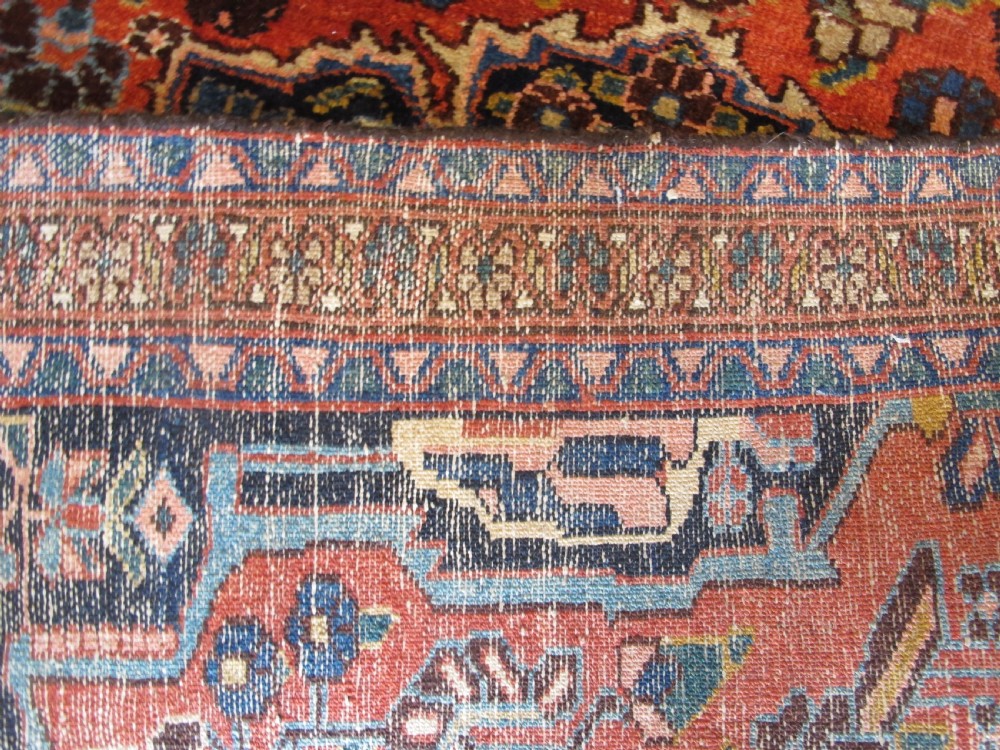 A long hand-knotted antique Persian Hamadan runner rug featuring terracotta red, navy blue, and cream floral medallion motifs throughout the central field. View XII