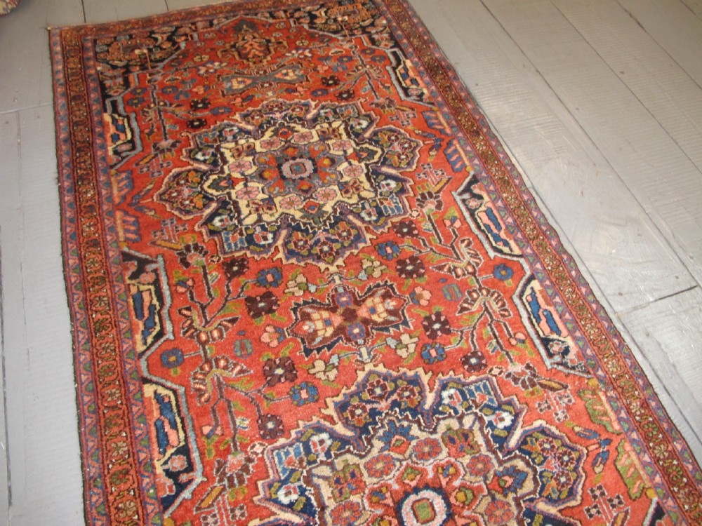 A long hand-knotted antique Persian Hamadan runner rug featuring terracotta red, navy blue, and cream floral medallion motifs throughout the central field. View XIII