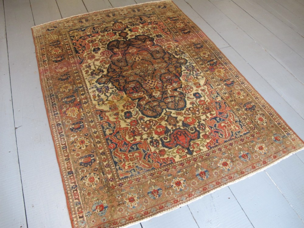 An antique hand-knotted Persian Isfahan area rug featuring an intricate dark blue and terracotta central medallion on an ivory floral field with decorative patterned borders. View II