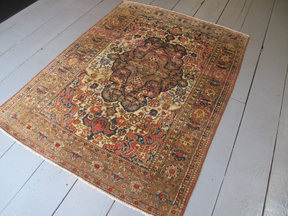 An antique hand-knotted Persian Isfahan area rug featuring an intricate dark blue and terracotta central medallion on an ivory floral field with decorative patterned borders. View III