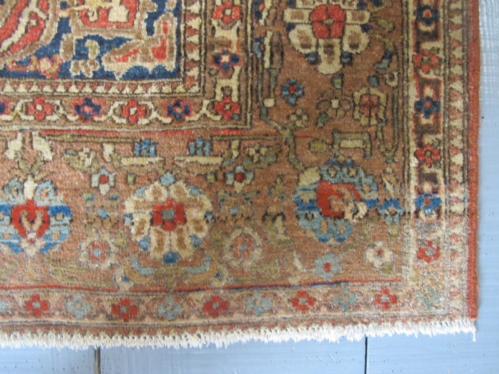 An antique hand-knotted Persian Isfahan area rug featuring an intricate dark blue and terracotta central medallion on an ivory floral field with decorative patterned borders. View IX