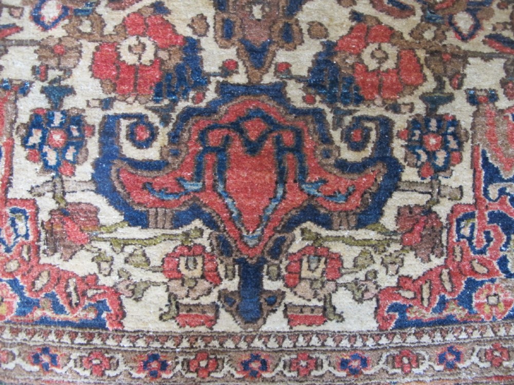 An antique hand-knotted Persian Isfahan area rug featuring an intricate dark blue and terracotta central medallion on an ivory floral field with decorative patterned borders. View XI