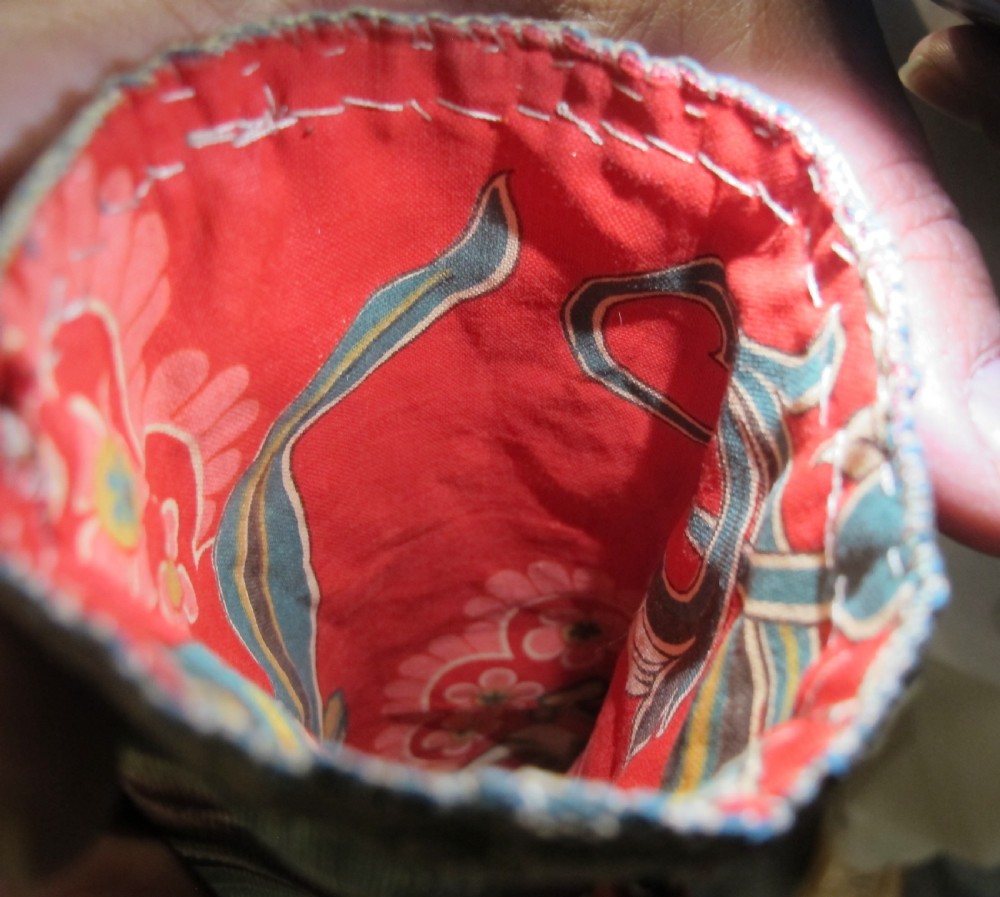 A rectangular double-sided silk ikat purse featuring colourful horizontal bands in pink, yellow, blue, and cream with a red tassel attached at the top opening. View VII