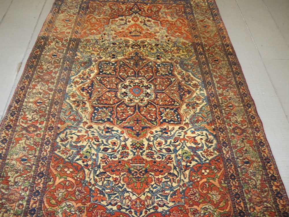 An antique hand-knotted Persian Isfahan rug featuring a central floral medallion surrounded by arabesque scrollwork and detailed multi-banded borders in terracotta red, navy blue, and cream. View II