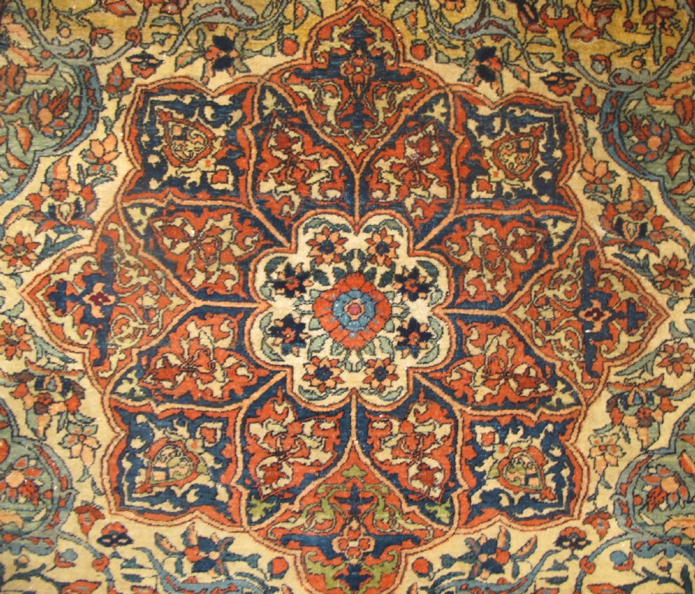 An antique hand-knotted Persian Isfahan rug featuring a central floral medallion surrounded by arabesque scrollwork and detailed multi-banded borders in terracotta red, navy blue, and cream. View III