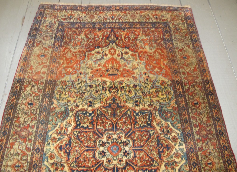 An antique hand-knotted Persian Isfahan rug featuring a central floral medallion surrounded by arabesque scrollwork and detailed multi-banded borders in terracotta red, navy blue, and cream. View IV