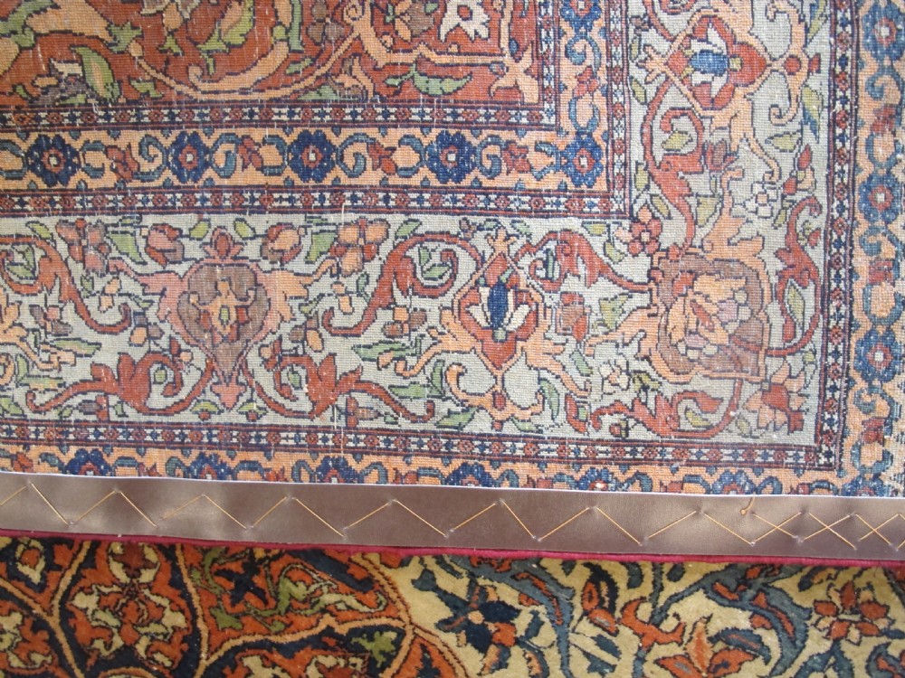 An antique hand-knotted Persian Isfahan rug featuring a central floral medallion surrounded by arabesque scrollwork and detailed multi-banded borders in terracotta red, navy blue, and cream. View VII