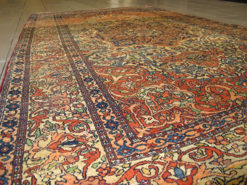 An antique hand-knotted Persian Isfahan rug featuring a central floral medallion surrounded by arabesque scrollwork and detailed multi-banded borders in terracotta red, navy blue, and cream. View IX