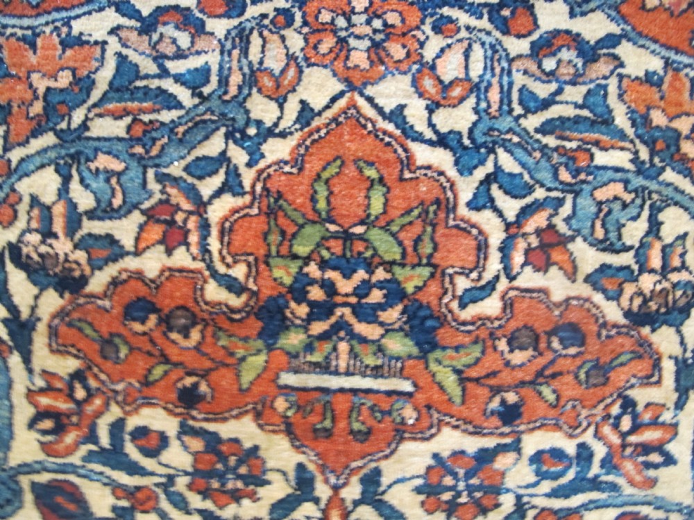 An antique hand-knotted Persian Isfahan rug featuring a central floral medallion surrounded by arabesque scrollwork and detailed multi-banded borders in terracotta red, navy blue, and cream. View X