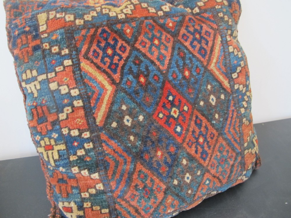 A square handwoven Kurdish wool cushion featuring geometric diamond motifs in blue, terracotta, and brown shades. View II