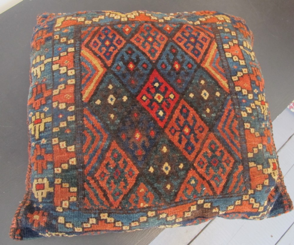 A square handwoven Kurdish wool cushion featuring geometric diamond motifs in blue, terracotta, and brown shades. View III