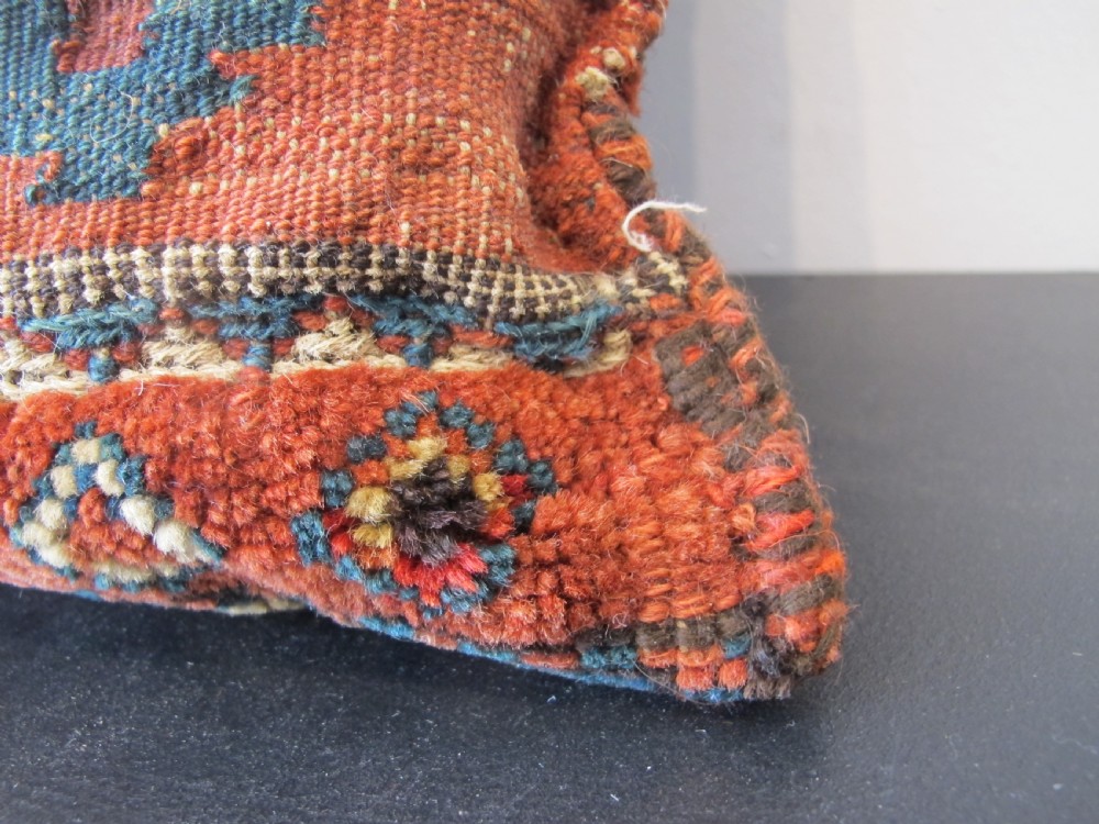 A square handwoven Kurdish wool cushion featuring geometric diamond motifs in blue, terracotta, and brown shades. View VI