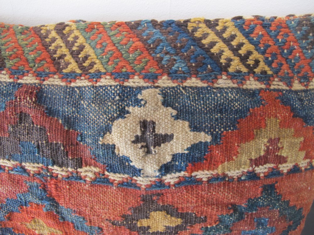 A square handwoven Kurdish wool cushion featuring geometric diamond motifs in blue, terracotta, and brown shades. View VII