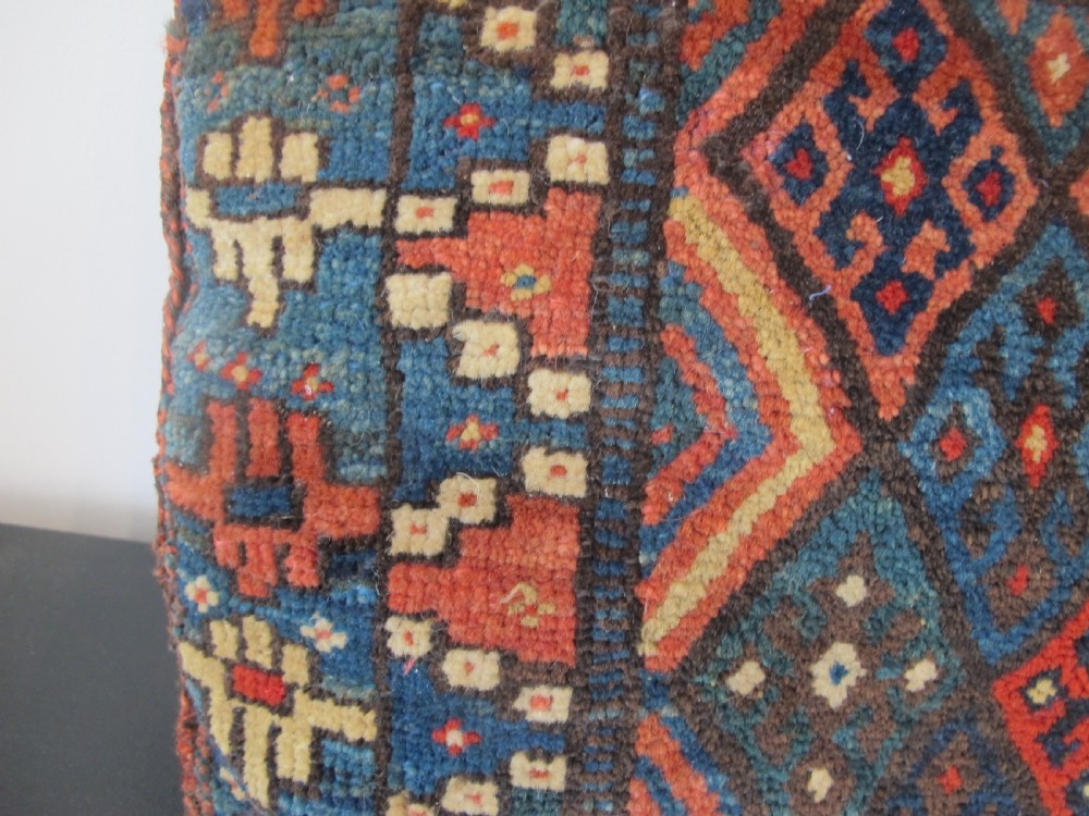 A square handwoven Kurdish wool cushion featuring geometric diamond motifs in blue, terracotta, and brown shades. View VIII
