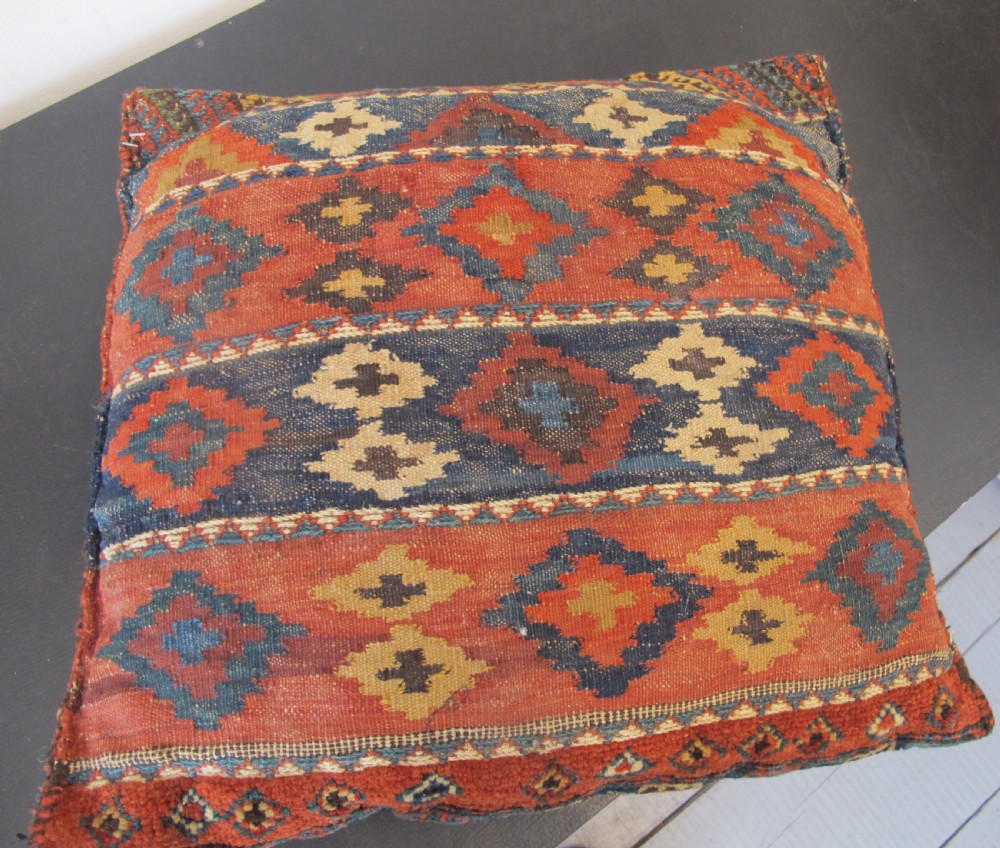 A square handwoven Kurdish wool cushion featuring geometric diamond motifs in blue, terracotta, and brown shades. View XI