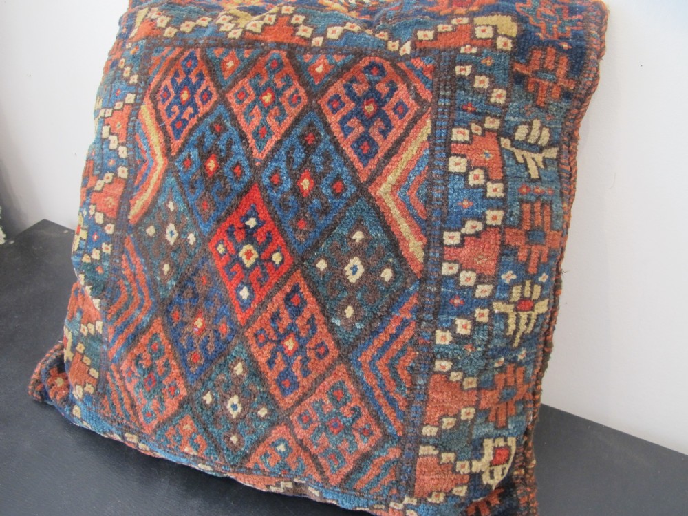 A square handwoven Kurdish wool cushion featuring geometric diamond motifs in blue, terracotta, and brown shades. View XII