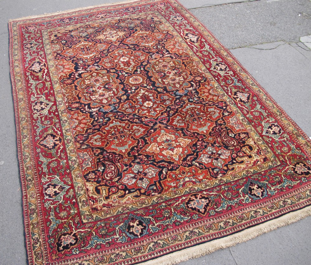 An antique hand-knotted Persian Isfahan rug featuring a dense floral lattice pattern in crimson red, navy blue, and cream with a detailed border. View II