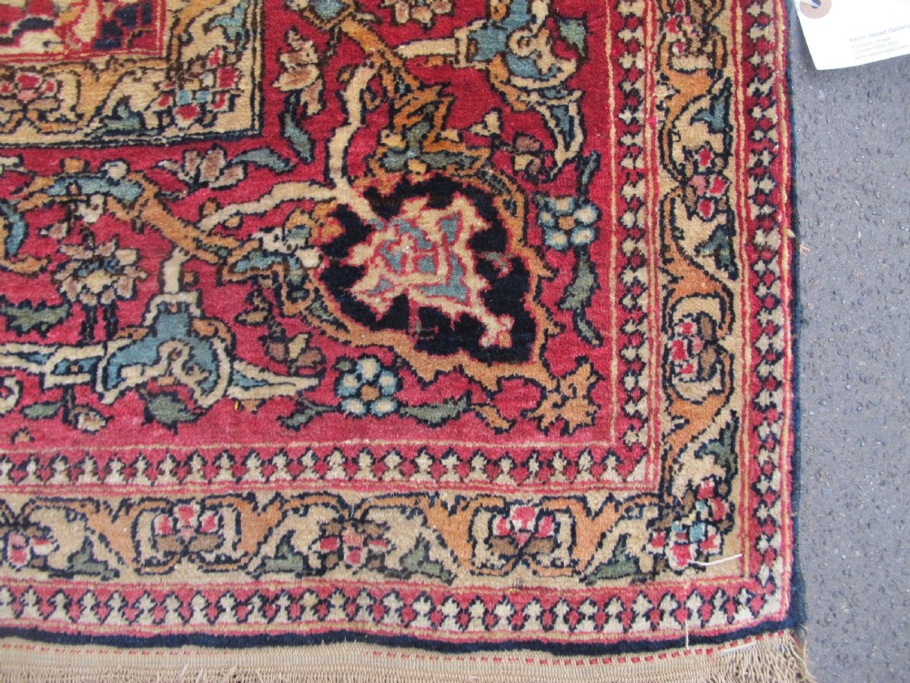 An antique hand-knotted Persian Isfahan rug featuring a dense floral lattice pattern in crimson red, navy blue, and cream with a detailed border. View IV