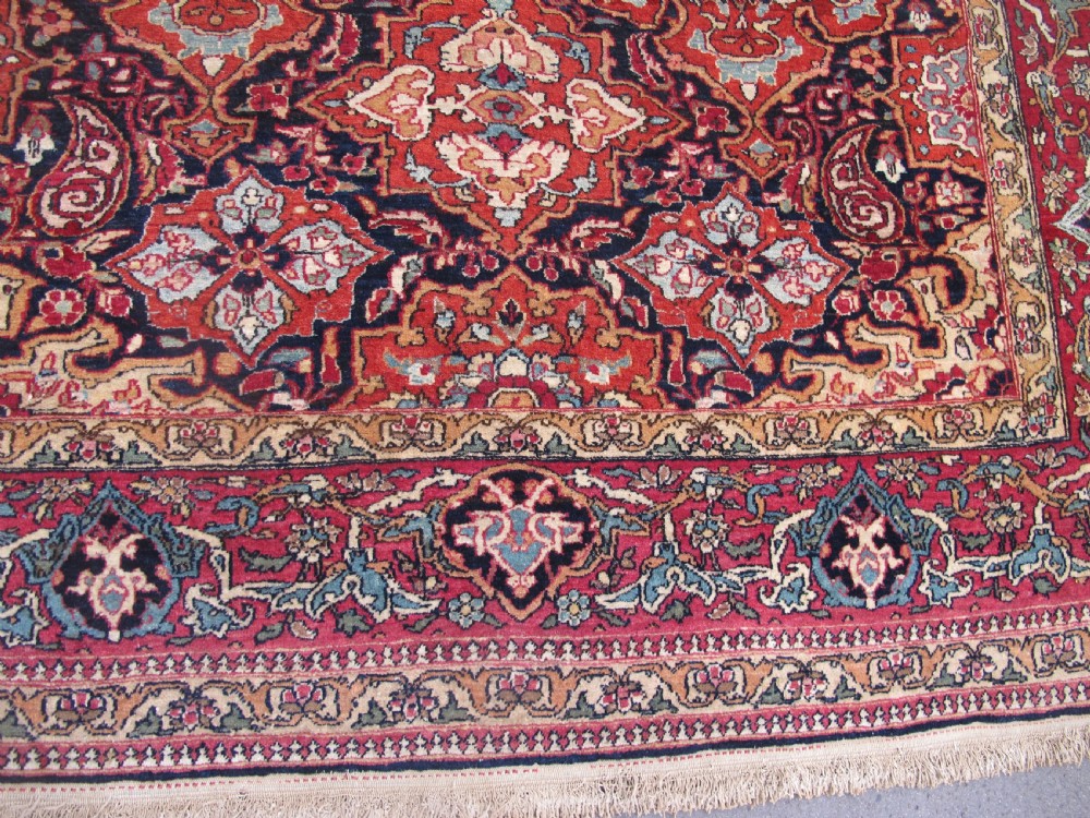 An antique hand-knotted Persian Isfahan rug featuring a dense floral lattice pattern in crimson red, navy blue, and cream with a detailed border. View XI