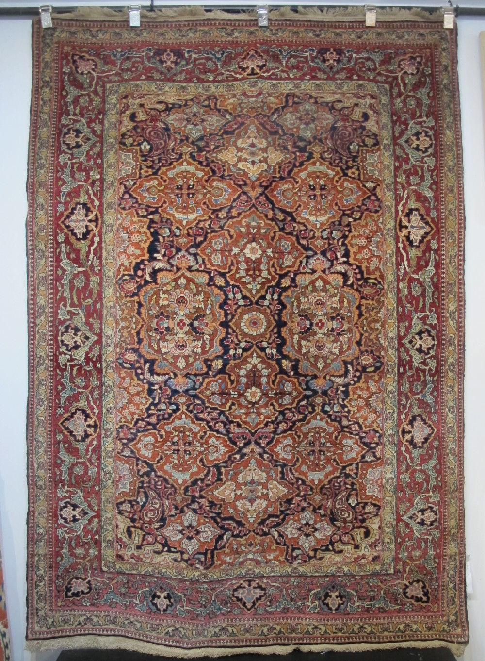 An antique hand-knotted Persian Isfahan rug featuring a dense floral lattice pattern in crimson red, navy blue, and cream with a detailed border. View XII