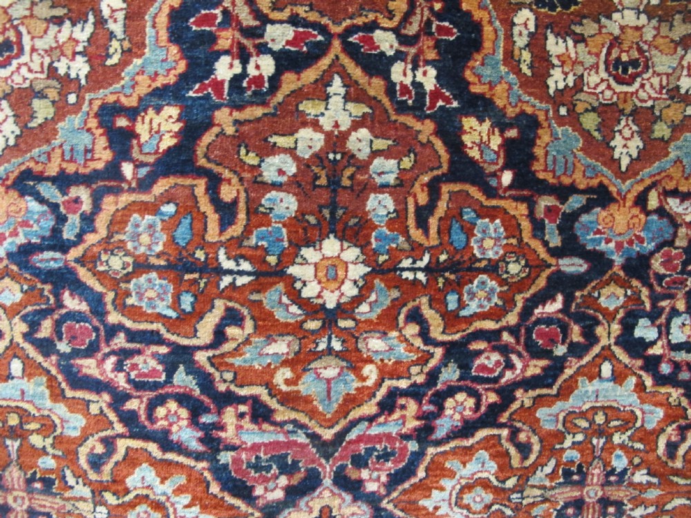 An antique hand-knotted Persian Isfahan rug featuring a dense floral lattice pattern in crimson red, navy blue, and cream with a detailed border. View XIV