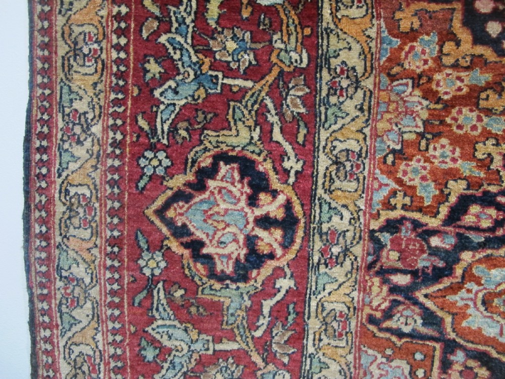 An antique hand-knotted Persian Isfahan rug featuring a dense floral lattice pattern in crimson red, navy blue, and cream with a detailed border. View XV