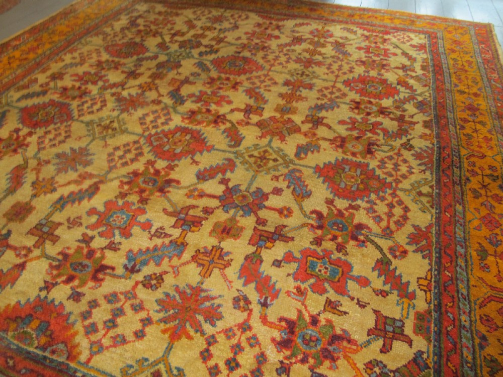 A large hand-knotted wool Oushak carpet featuring a golden-yellow field with geometric medallion motifs bordered by wide terracotta and orange patterned bands. View II