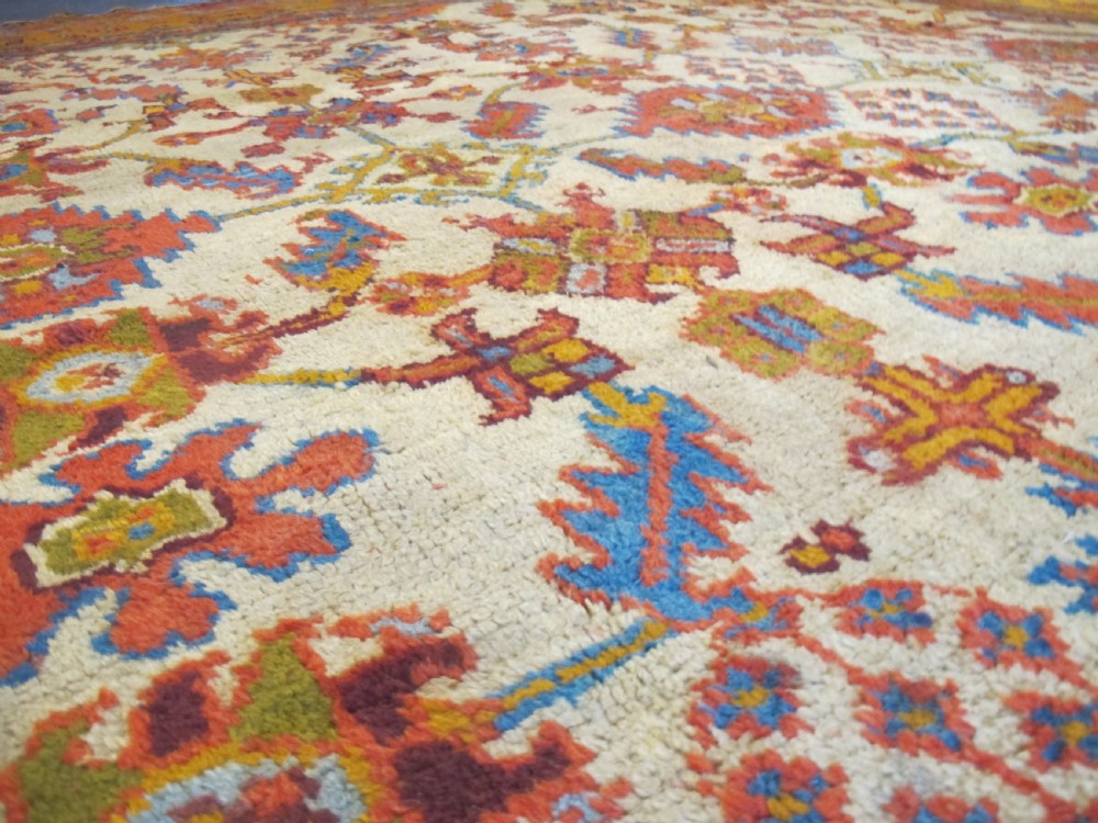 A large hand-knotted wool Oushak carpet featuring a golden-yellow field with geometric medallion motifs bordered by wide terracotta and orange patterned bands. View V