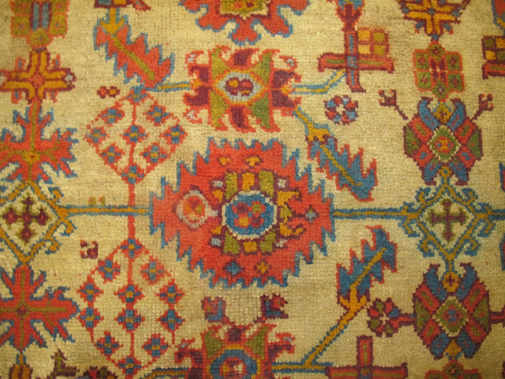 A large hand-knotted wool Oushak carpet featuring a golden-yellow field with geometric medallion motifs bordered by wide terracotta and orange patterned bands. View IX