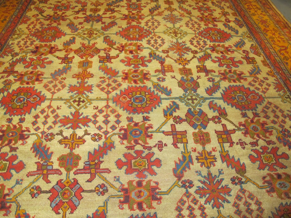 A large hand-knotted wool Oushak carpet featuring a golden-yellow field with geometric medallion motifs bordered by wide terracotta and orange patterned bands. View XI