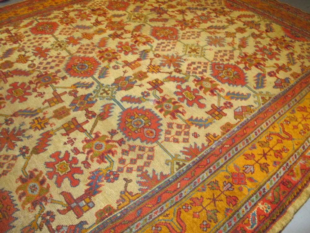 A large hand-knotted wool Oushak carpet featuring a golden-yellow field with geometric medallion motifs bordered by wide terracotta and orange patterned bands. View XII