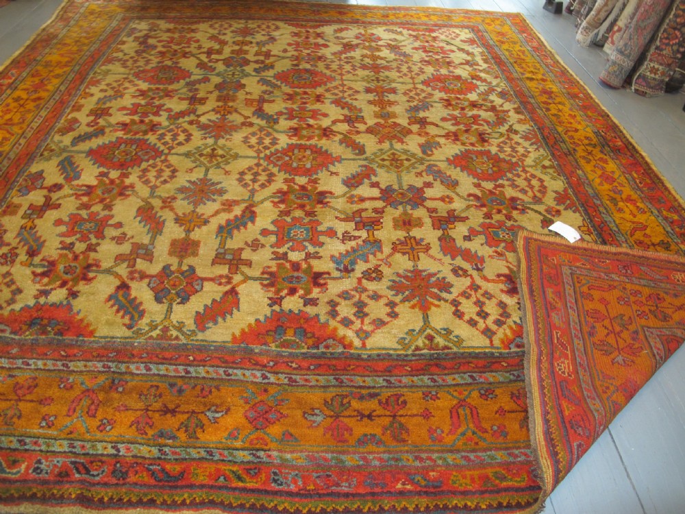 A large hand-knotted wool Oushak carpet featuring a golden-yellow field with geometric medallion motifs bordered by wide terracotta and orange patterned bands. View XVI