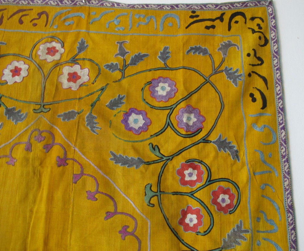 An early 20th-century yellow silk textile from Uzbekistan featuring hand-embroidered floral motifs, a central arch design, and calligraphic borders. View IV