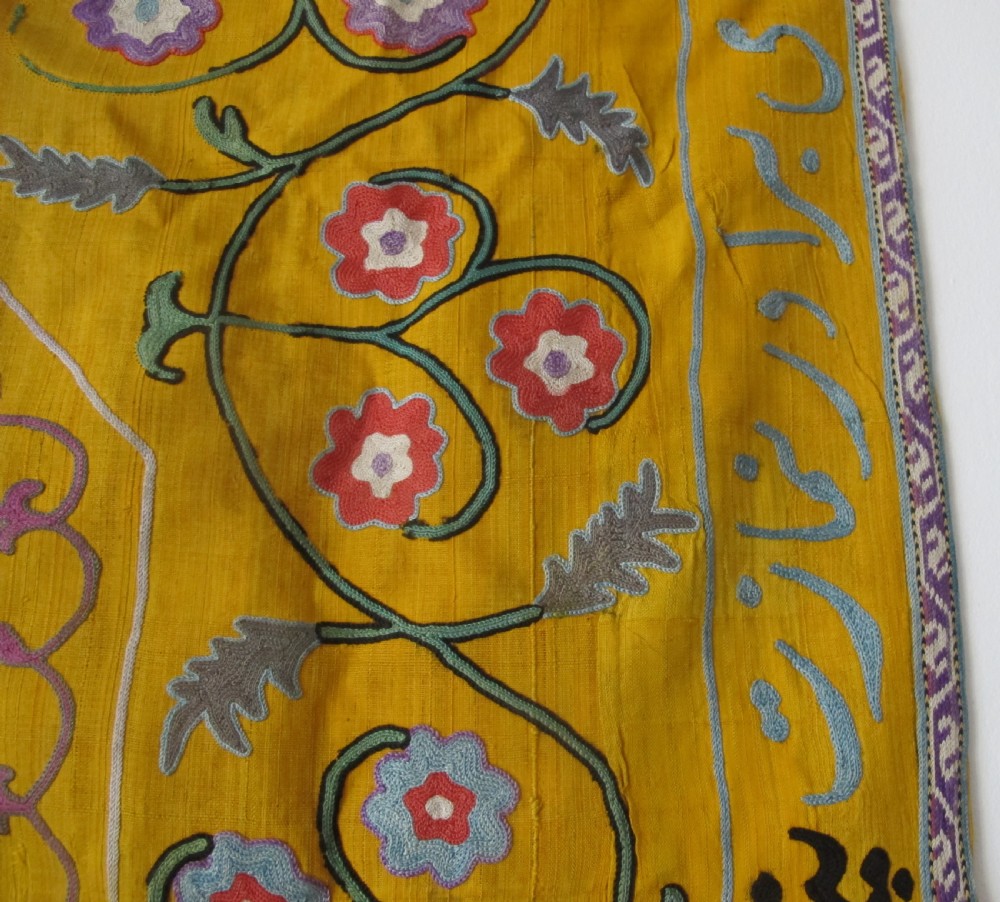 An early 20th-century yellow silk textile from Uzbekistan featuring hand-embroidered floral motifs, a central arch design, and calligraphic borders. View VII