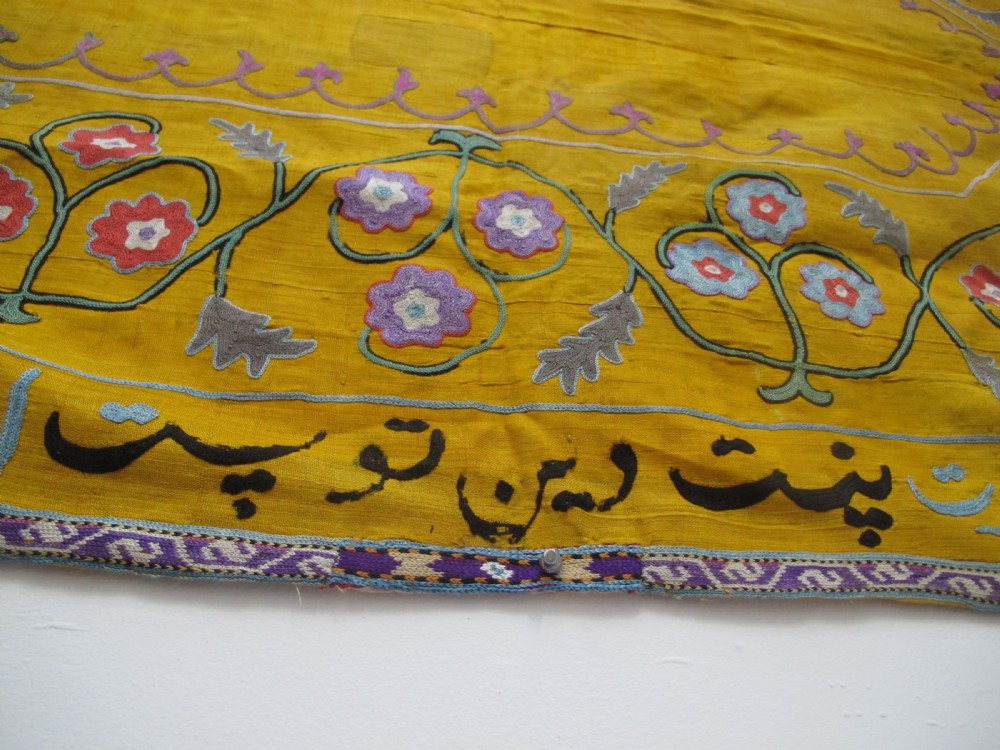 An early 20th-century yellow silk textile from Uzbekistan featuring hand-embroidered floral motifs, a central arch design, and calligraphic borders. View VIII