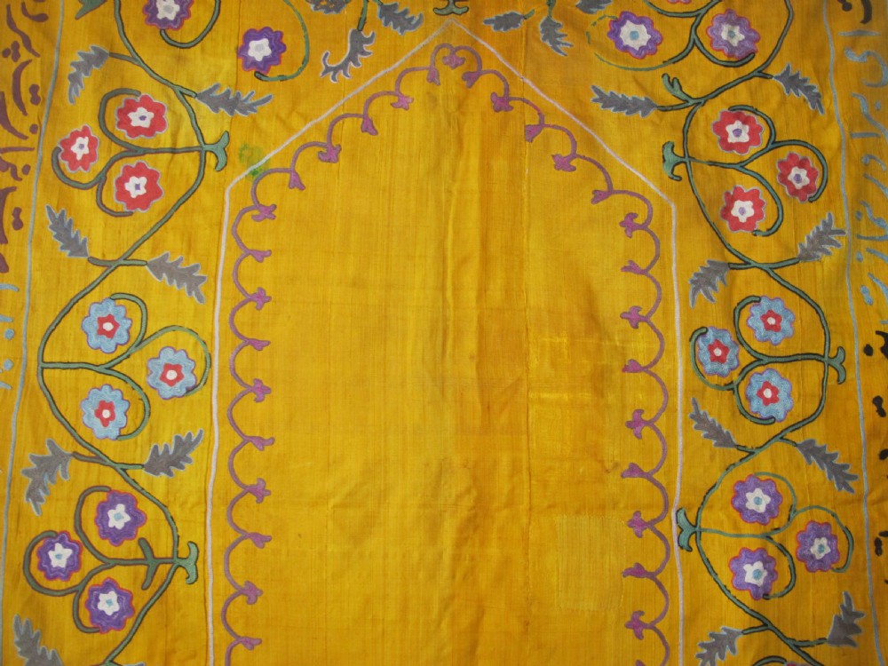 An early 20th-century yellow silk textile from Uzbekistan featuring hand-embroidered floral motifs, a central arch design, and calligraphic borders. View XIII