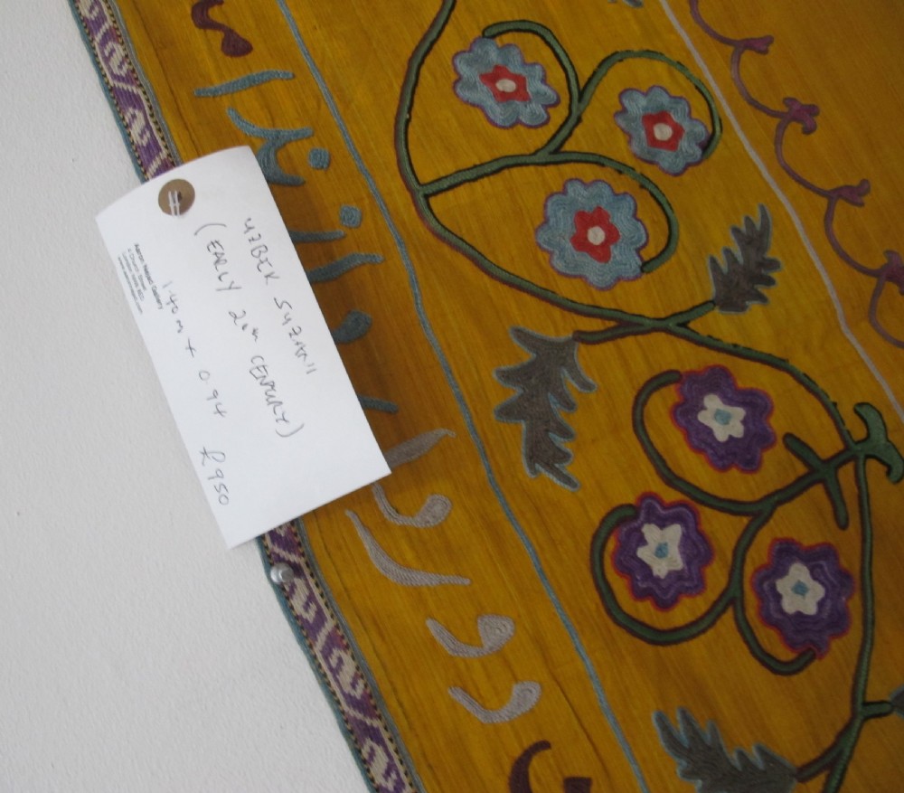 An early 20th-century yellow silk textile from Uzbekistan featuring hand-embroidered floral motifs, a central arch design, and calligraphic borders. View XIV