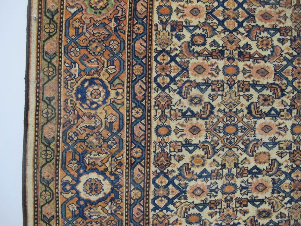 A rectangular antique Persian Fereghan rug with a detailed cream, terracotta, and navy Herati pattern bordered by intricate geometric bands. View III