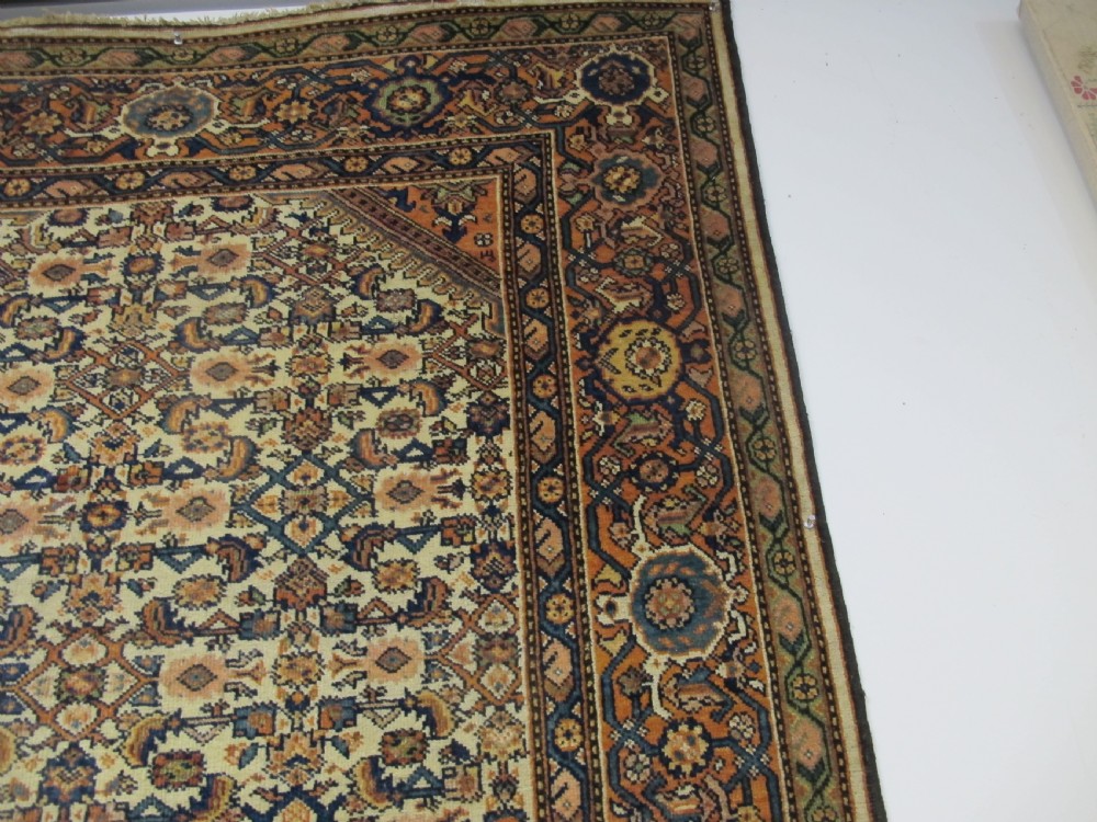 A rectangular antique Persian Fereghan rug with a detailed cream, terracotta, and navy Herati pattern bordered by intricate geometric bands. View IV