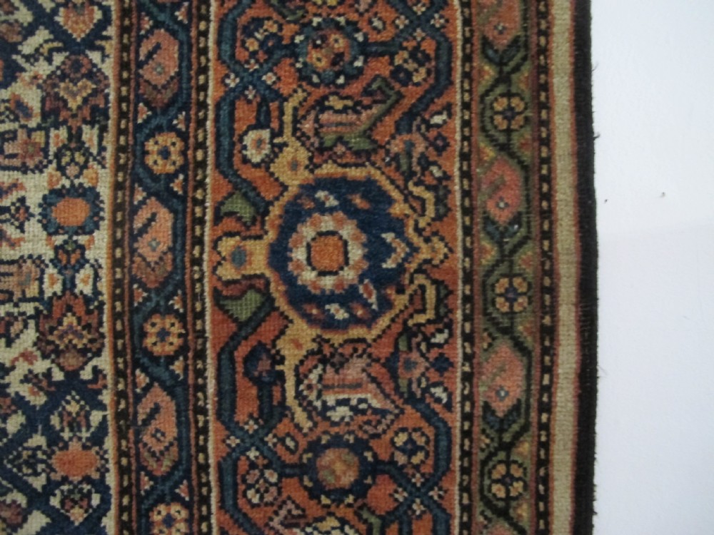 A rectangular antique Persian Fereghan rug with a detailed cream, terracotta, and navy Herati pattern bordered by intricate geometric bands. View V