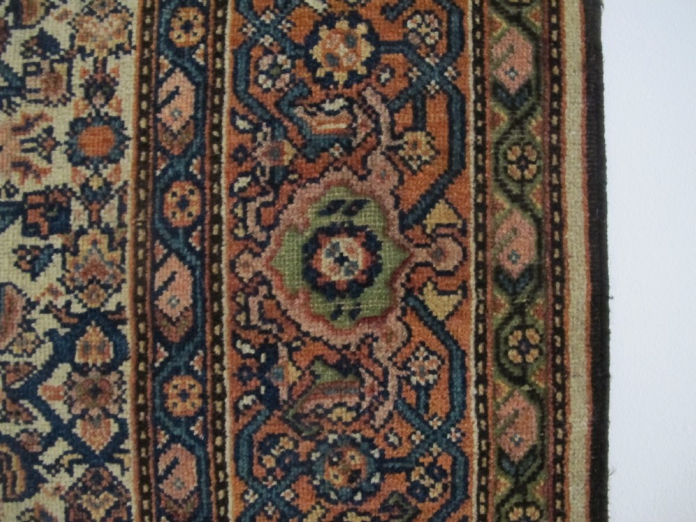 A rectangular antique Persian Fereghan rug with a detailed cream, terracotta, and navy Herati pattern bordered by intricate geometric bands. View VI
