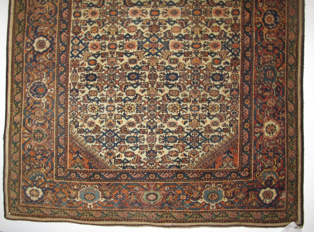 A rectangular antique Persian Fereghan rug with a detailed cream, terracotta, and navy Herati pattern bordered by intricate geometric bands. View X