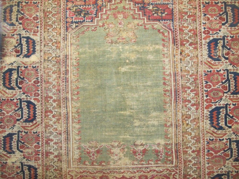 An 18th-century hand-knotted Ghiordes prayer rug featuring a central pale green mihrab niche framed by intricate floral borders in red, blue, and beige. View II